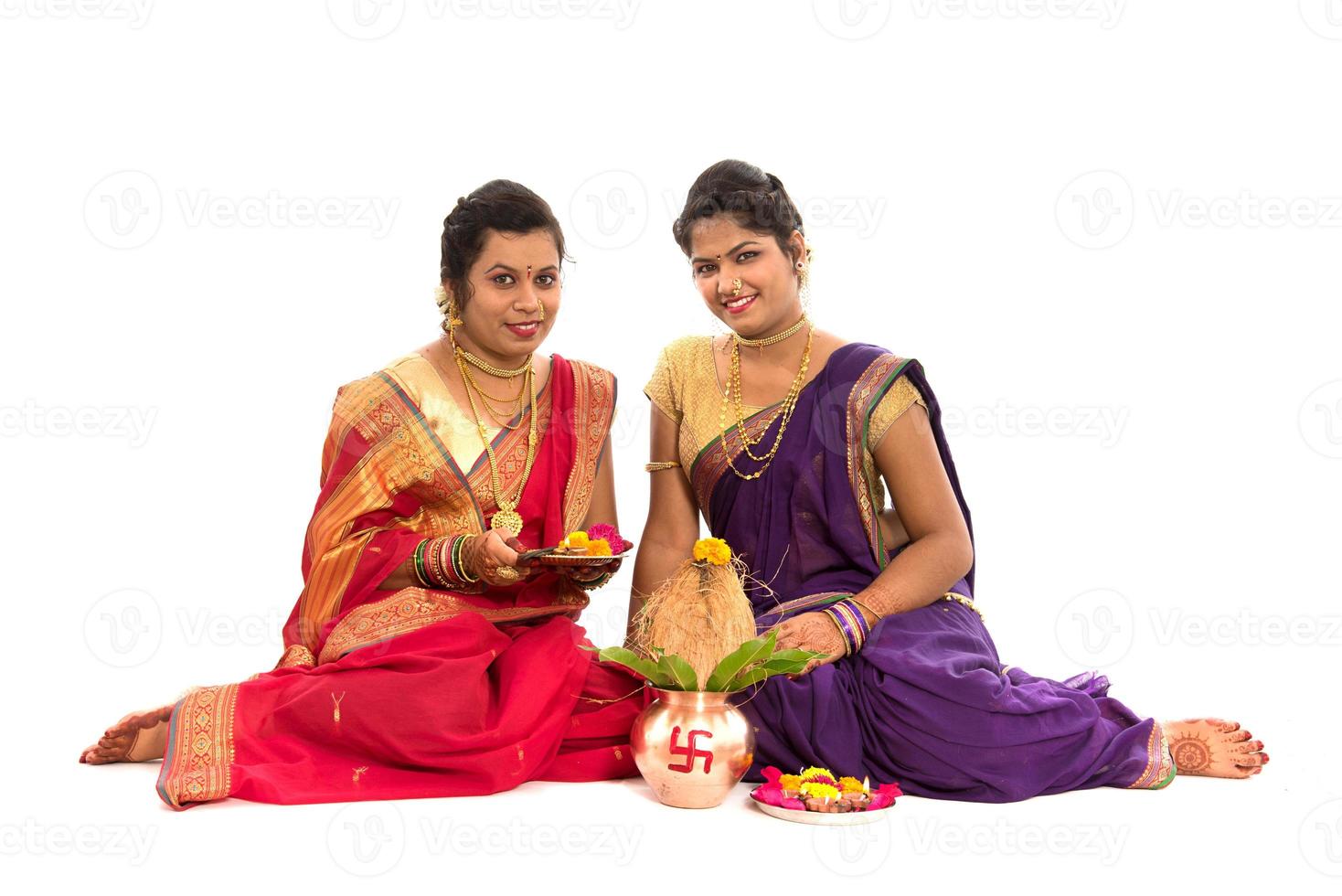 sorelle tradizionali indiane che eseguono il culto, festival indiano, kalash di rame con cocco e foglia di mango con decorazione floreale, essenziale nella puja indù. foto
