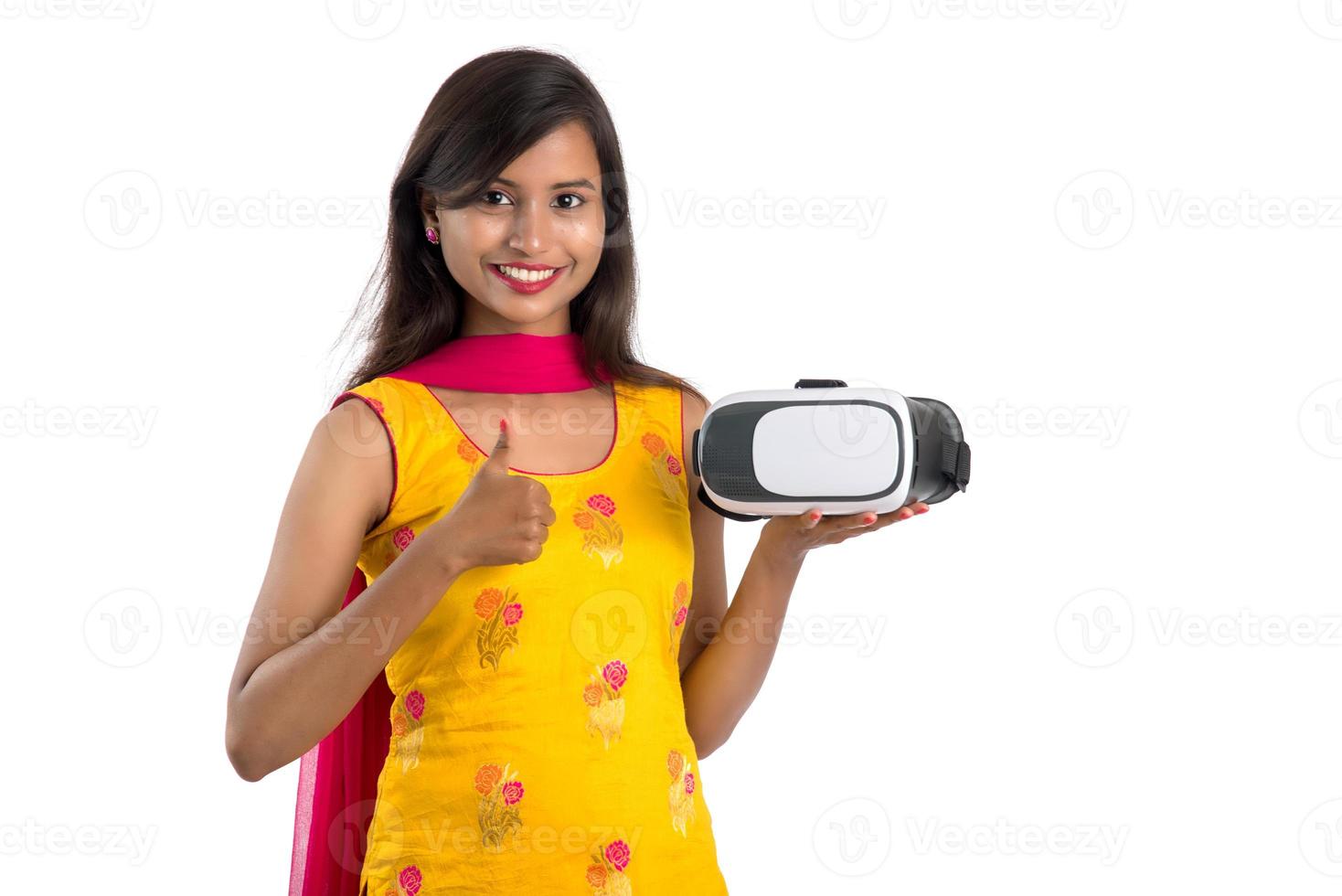 ragazza tradizionale indiana che tiene e mostra dispositivo vr, scatola vr, occhiali, cuffie per occhiali per realtà virtuale 3d, ragazza con moderna tecnologia futura di imaging su sfondo bianco. foto