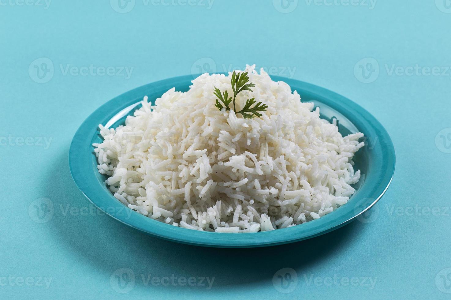 riso basmati bianco cotto cotto con coriandolo in un piatto blu su sfondo blu foto