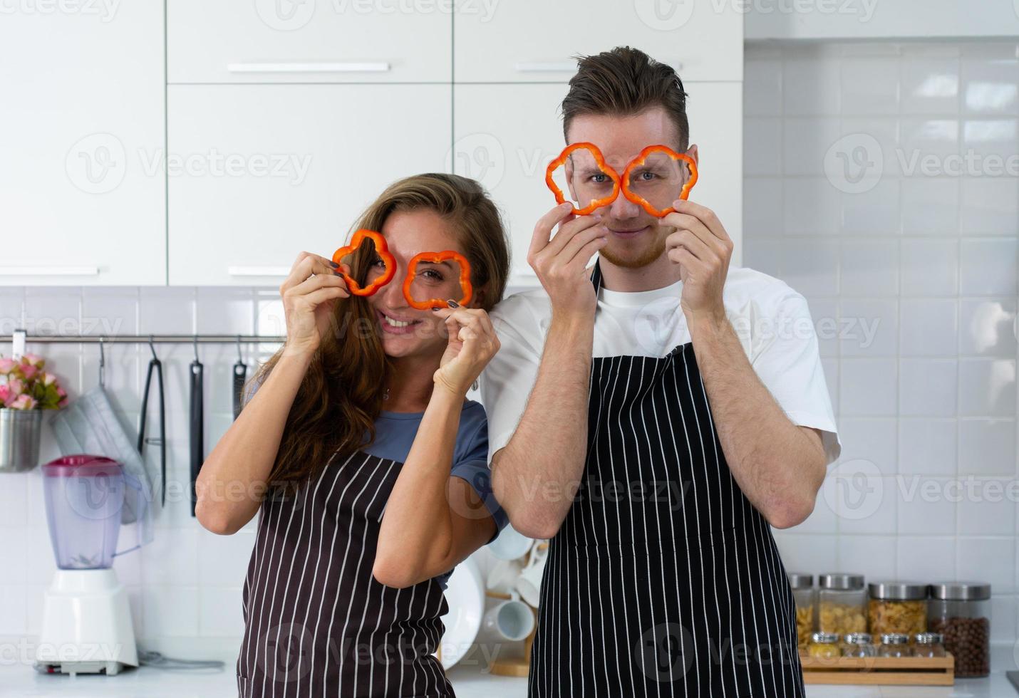 giovane coppia caucasica che tiene la frutta in mano e in piedi in cucina per preparare la colazione foto