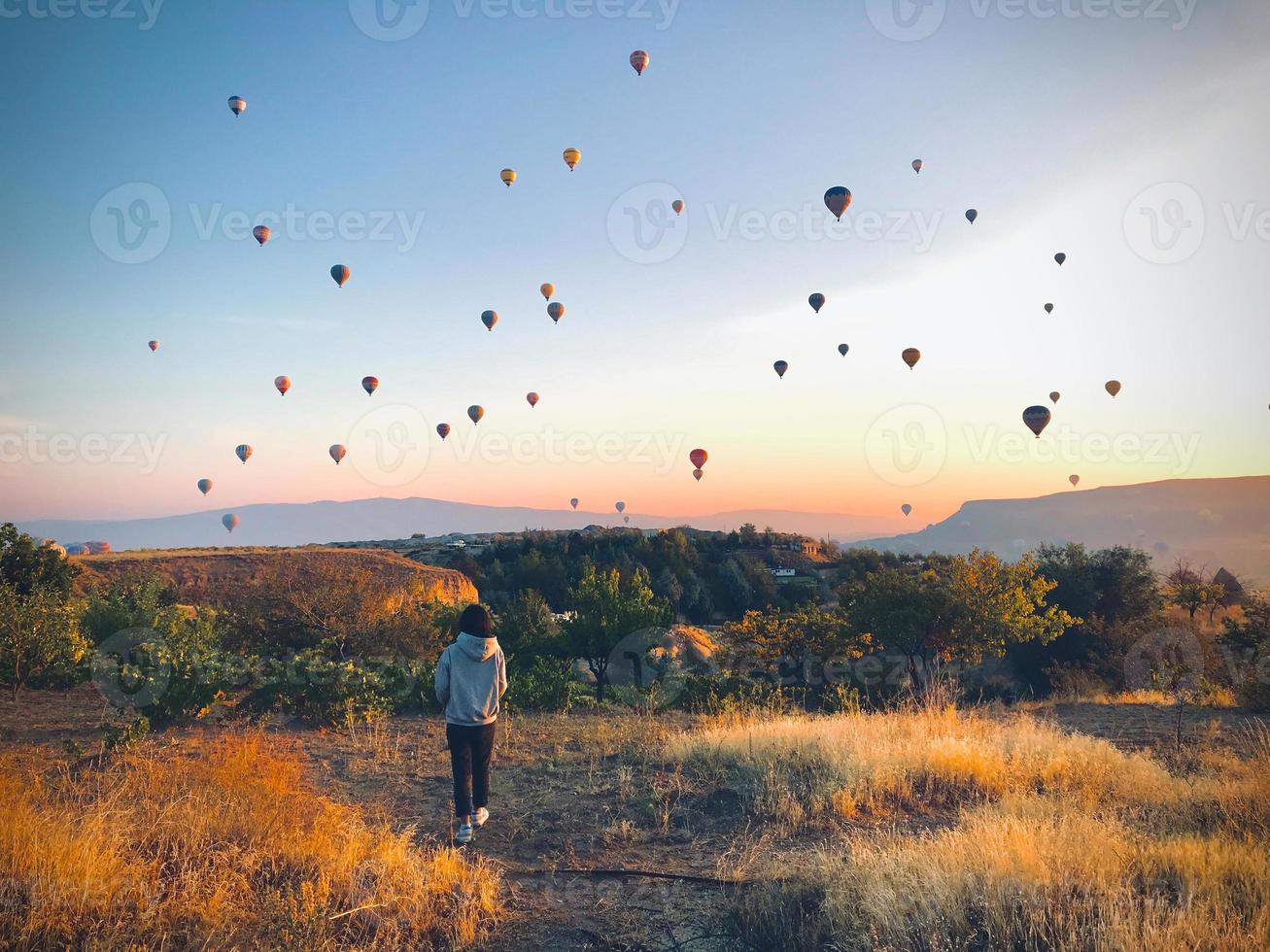 Vista posteriore donna caucasica viaggiatore solista camminare e guardare i palloncini spettacolo in cappadocia in viaggio avventura foto