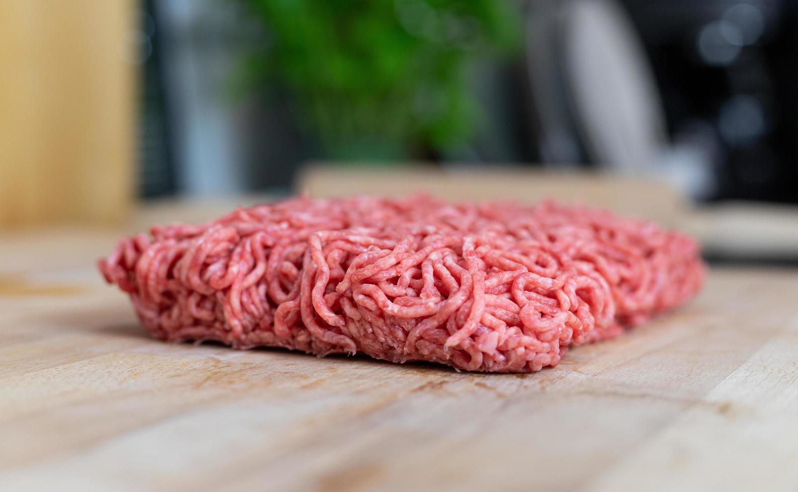 un pezzo di manzo crudo sdraiato su un tavolo di legno. preparazione di prodotti per la cottura. foto