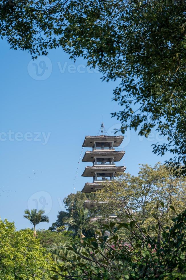 una torre sotto il cielo azzurro e gli alberi verdi foto