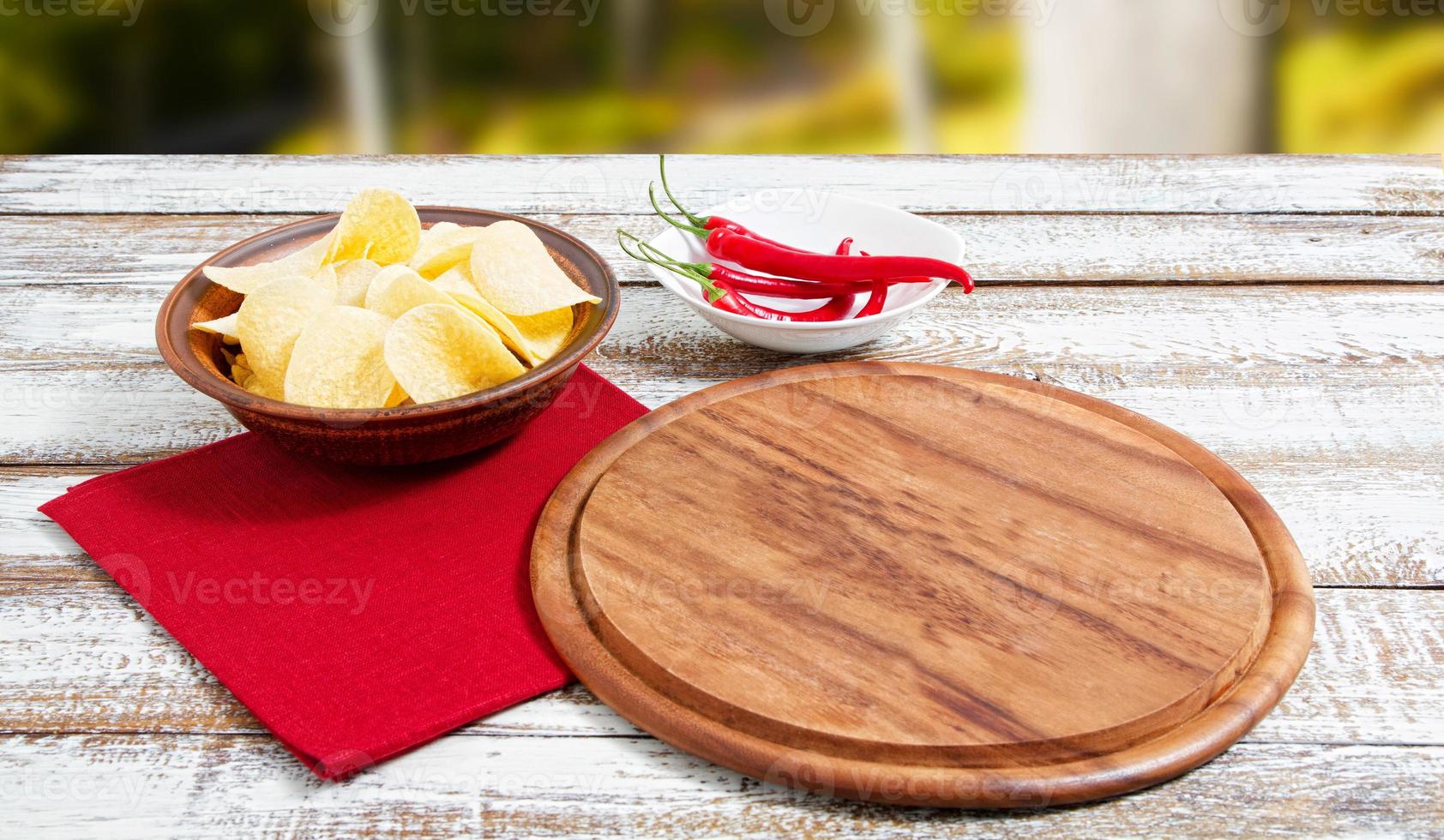 patatine piccanti al peperoncino rosso e tavola vuota su un tavolo di legno foto