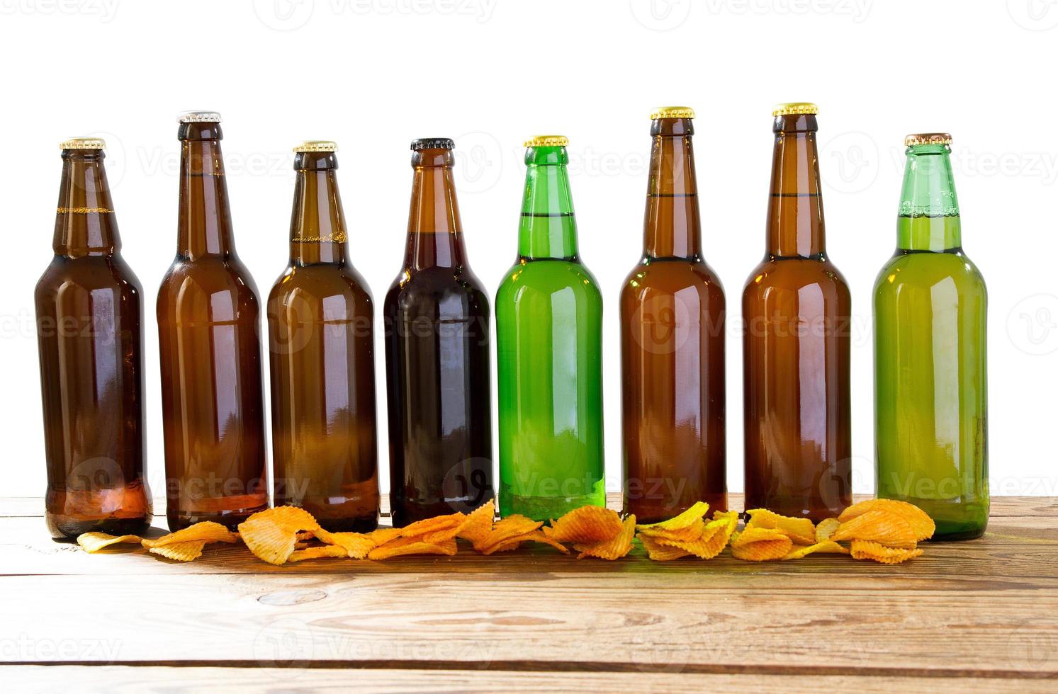 impostare bottiglie di vetro di birra mock up senza etichetta e patatine sul tavolo di legno isolato, spazio di copia foto