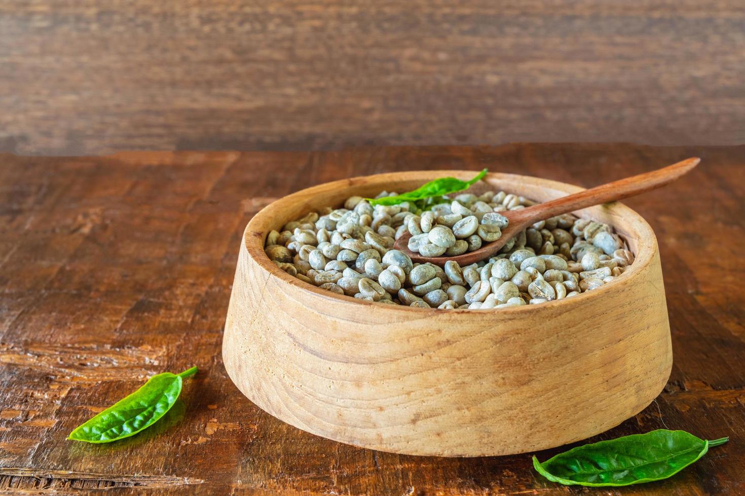 chicchi di caffè verde non tostati in una ciotola di legno foto