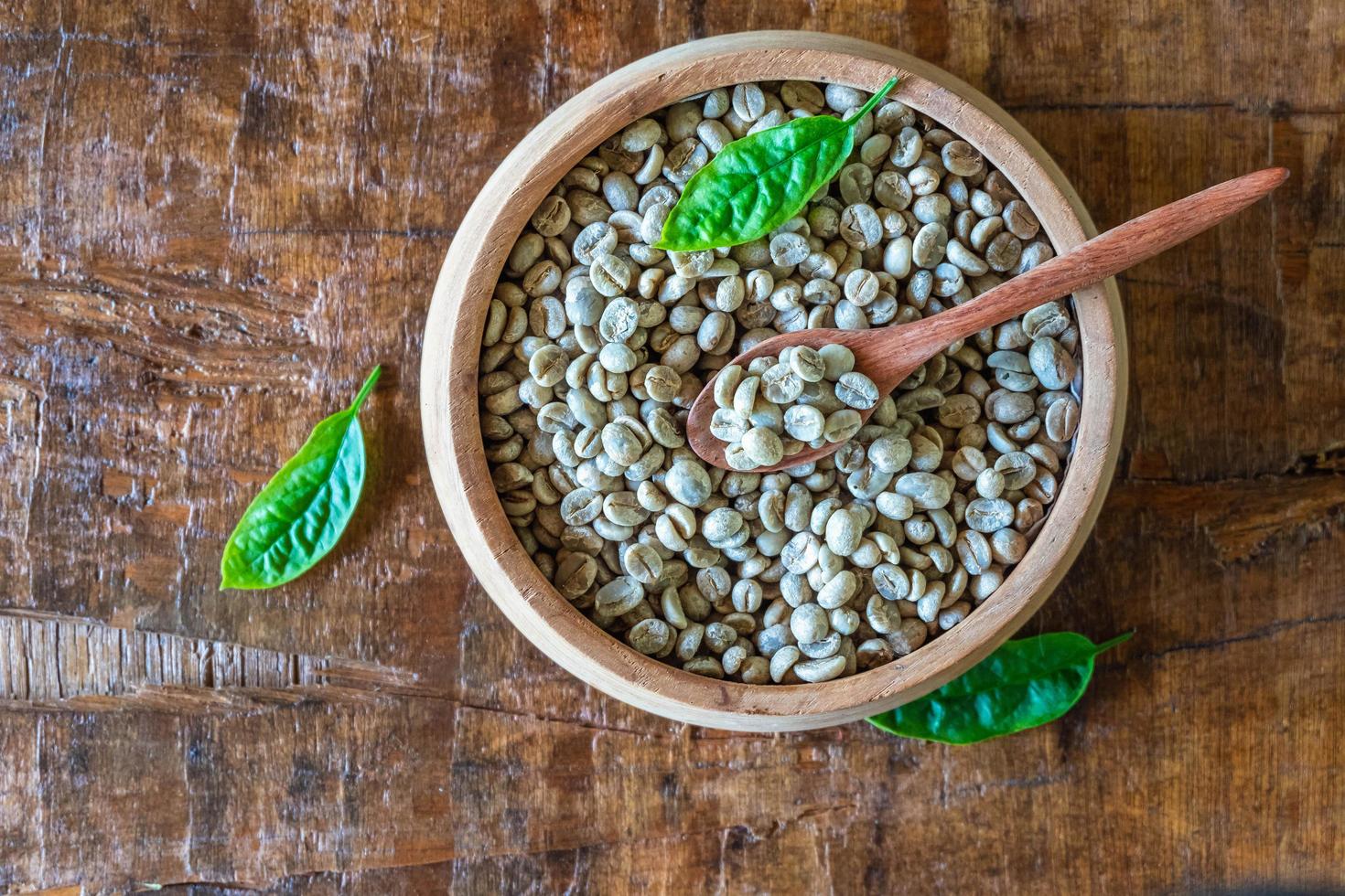 chicchi di caffè verde non tostati in una ciotola di legno foto