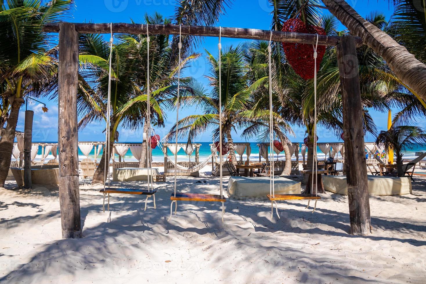 sedili altalena in legno in un bellissimo resort sulla spiaggia con tettoia e mare sullo sfondo foto