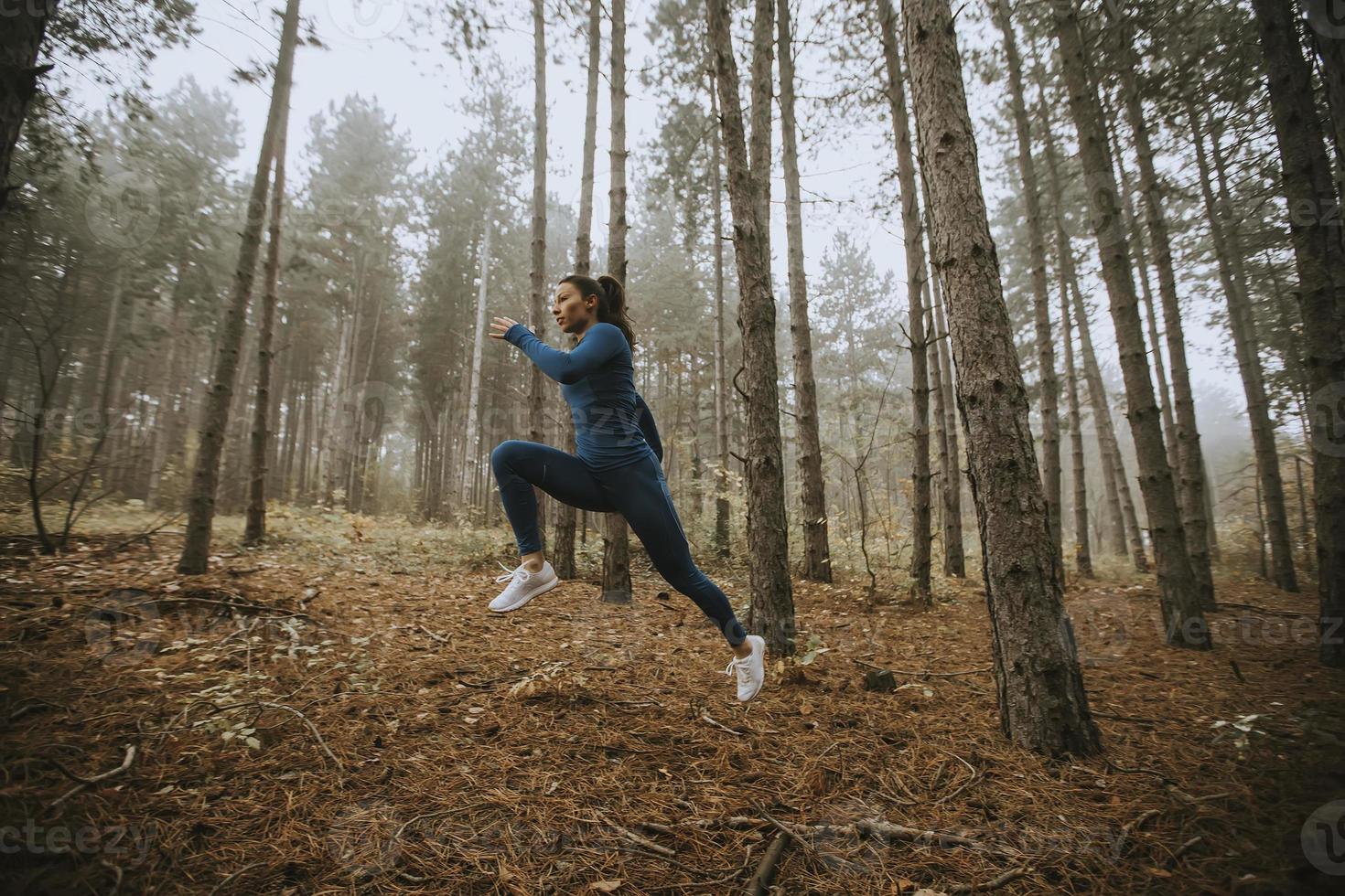 giovane donna che corre verso la telecamera sul sentiero nel bosco in autunno foto