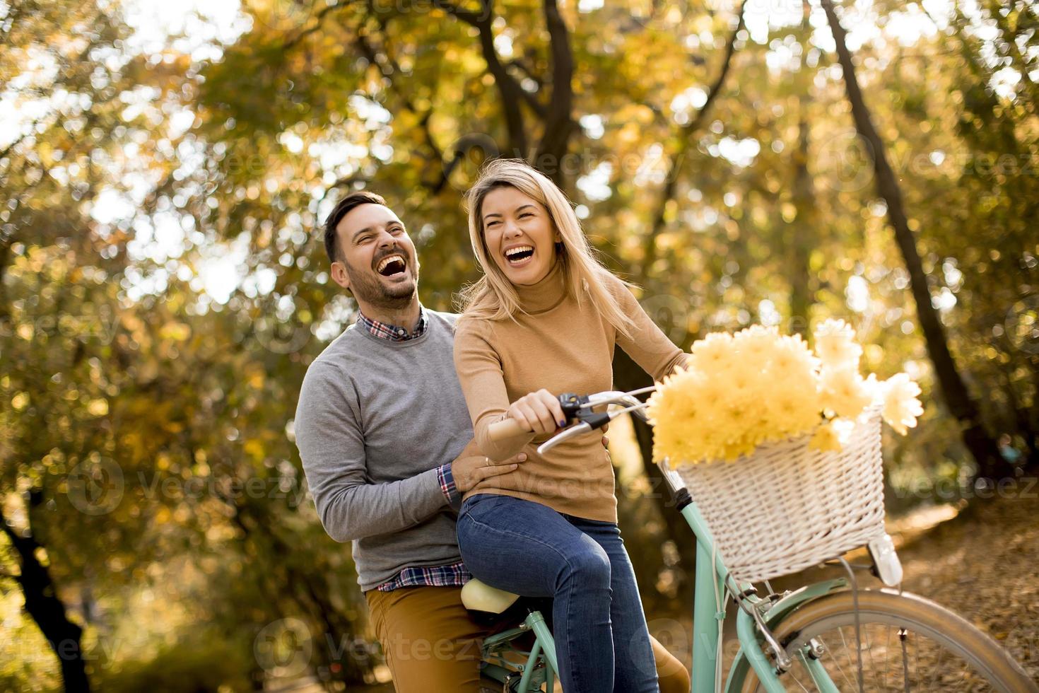 giovane coppia attiva che si diverte in bicicletta nel parco autunnale dorato foto