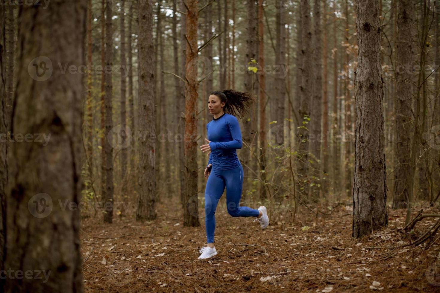 giovane donna che corre sul sentiero nel bosco in autunno foto