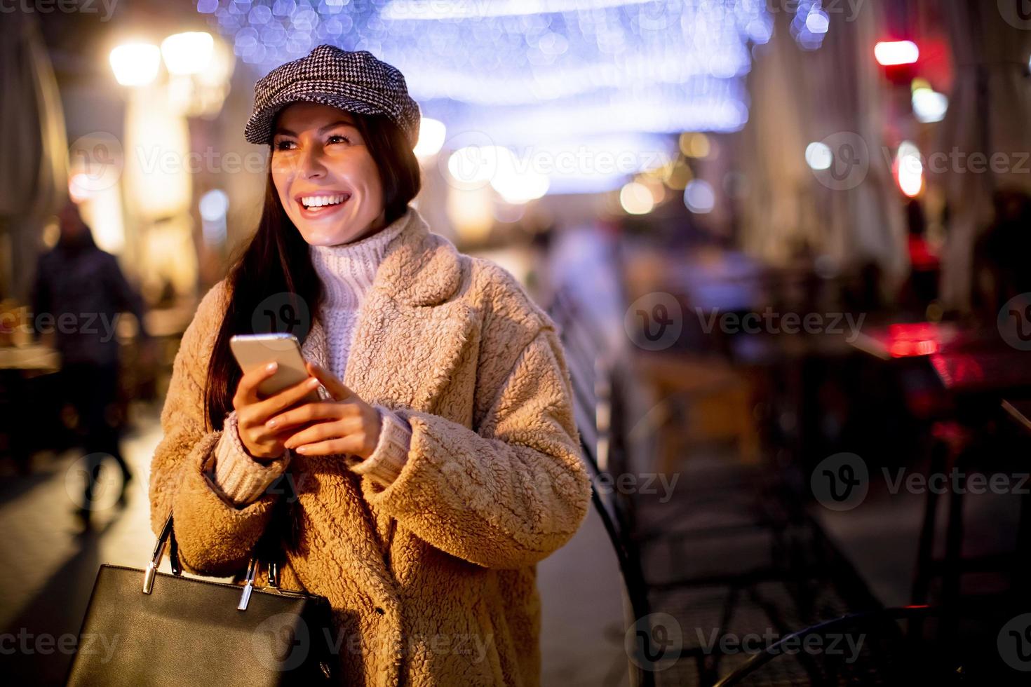 bella giovane donna che usa il suo telefono cellulare in strada a Natale foto