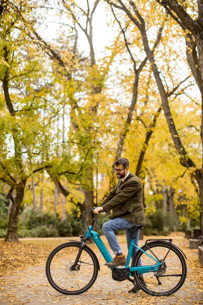 giovane con bicicletta elettrica nel parco autunnale foto