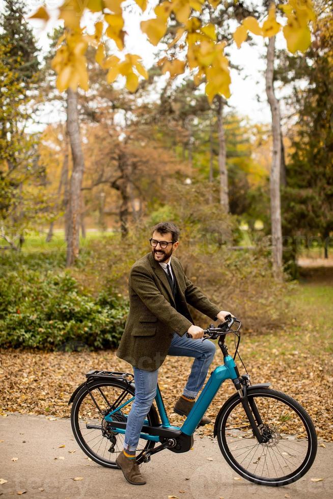 giovane con bicicletta elettrica nel parco autunnale foto