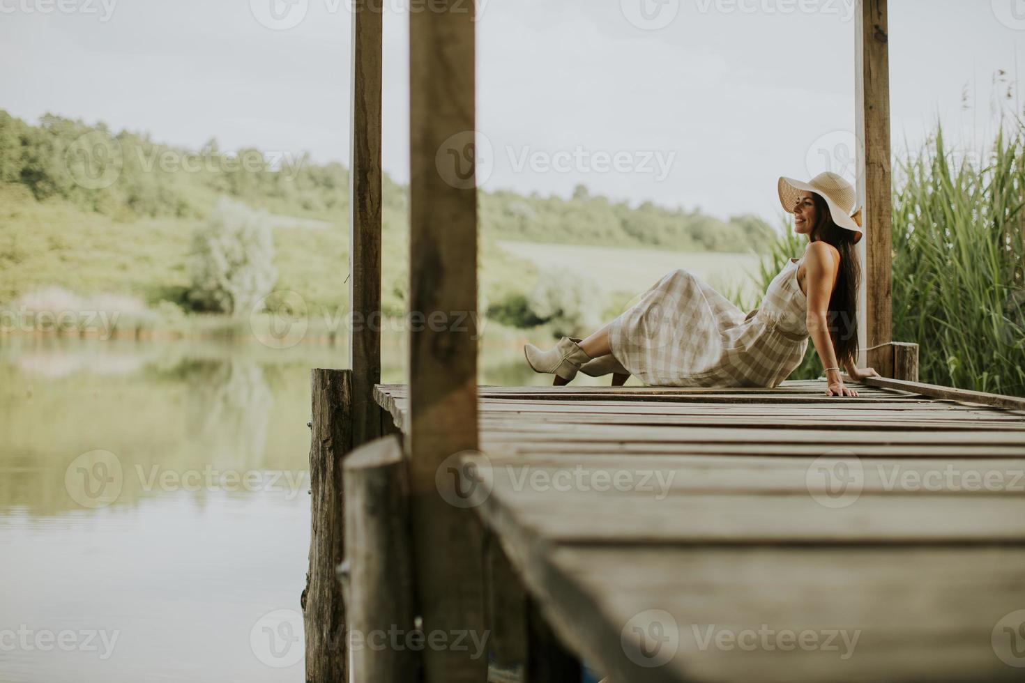 rilassante giovane donna sul molo di legno al lago foto