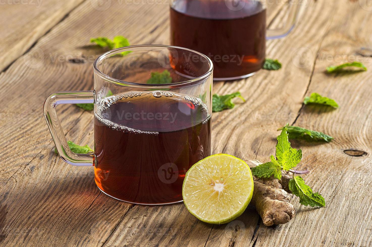 tazza di tè con zenzero, limone e menta su tavola di legno wooden foto