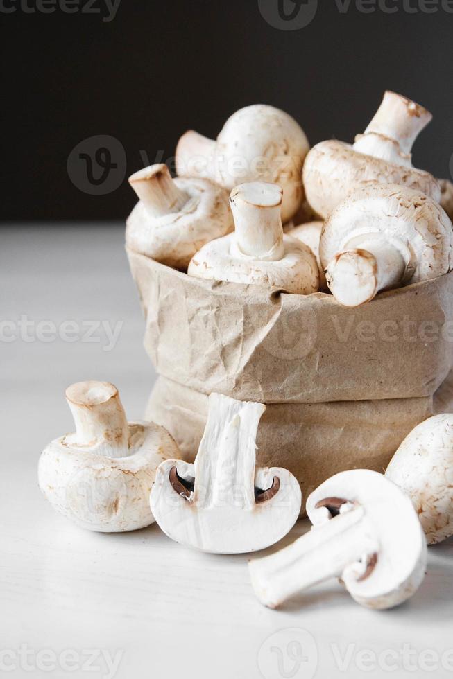 funghi prataioli in sacchetto di carta su un tavolo di legno bianco. posto per testo o pubblicità foto