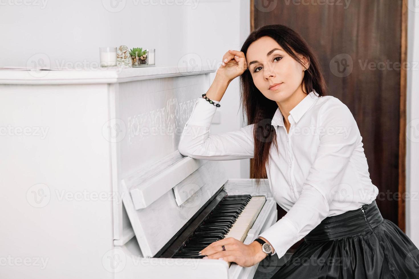 bella donna vestita in camicia bianca, suonare il pianoforte bianco. posto per testo o pubblicità foto