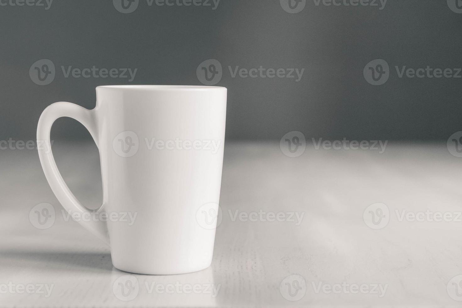 tazza di ceramica bianca sul tavolo di legno bianco su sfondo grigio. posto per testo o pubblicità foto