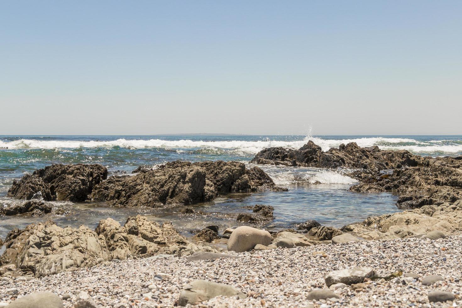 onde forti, scogliere di pietre sul mare, lungomare di città del capo. foto