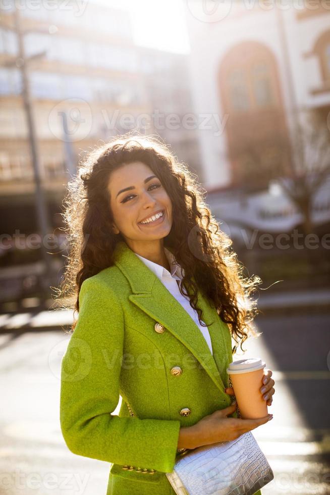 giovane donna che tiene il caffè da asporto per strada foto