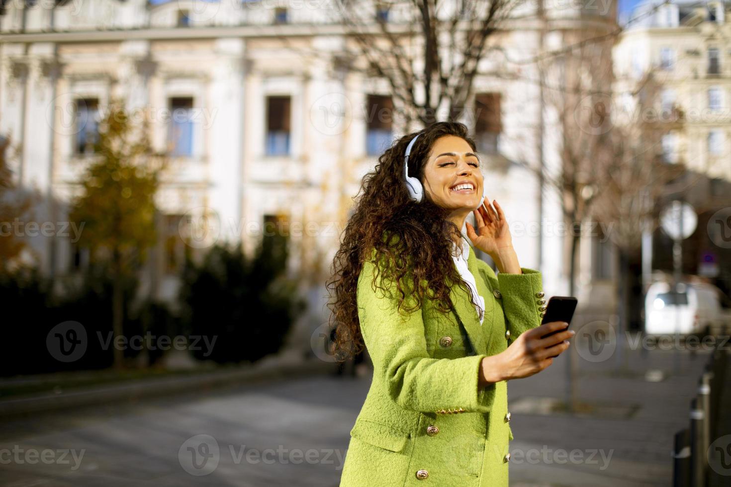 giovane donna che ascolta musica con lo smartphone per strada foto