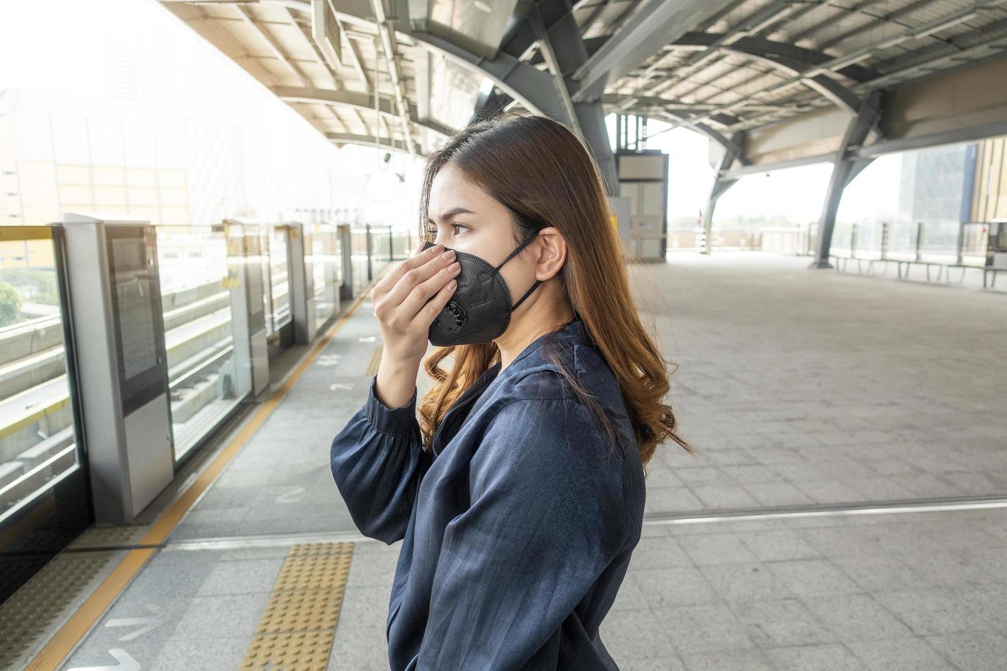 bella donna che indossa una maschera antipolvere protegge l'inquinamento atmosferico e pm 2.5 sulla città di strada foto