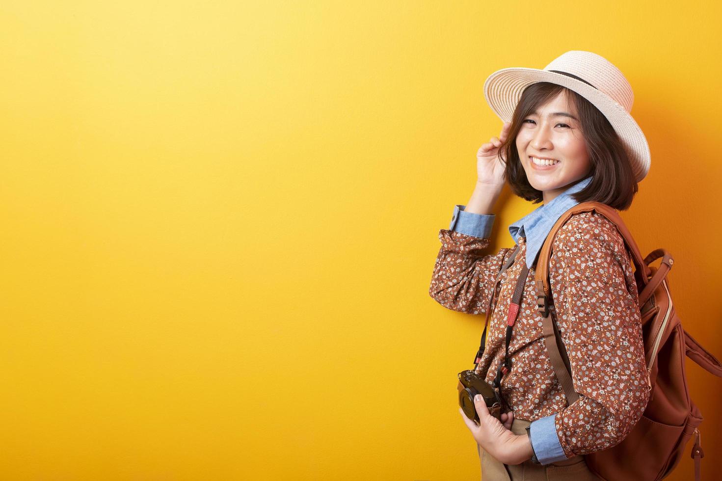 felice giovane donna turistica asiatica su sfondo giallo foto