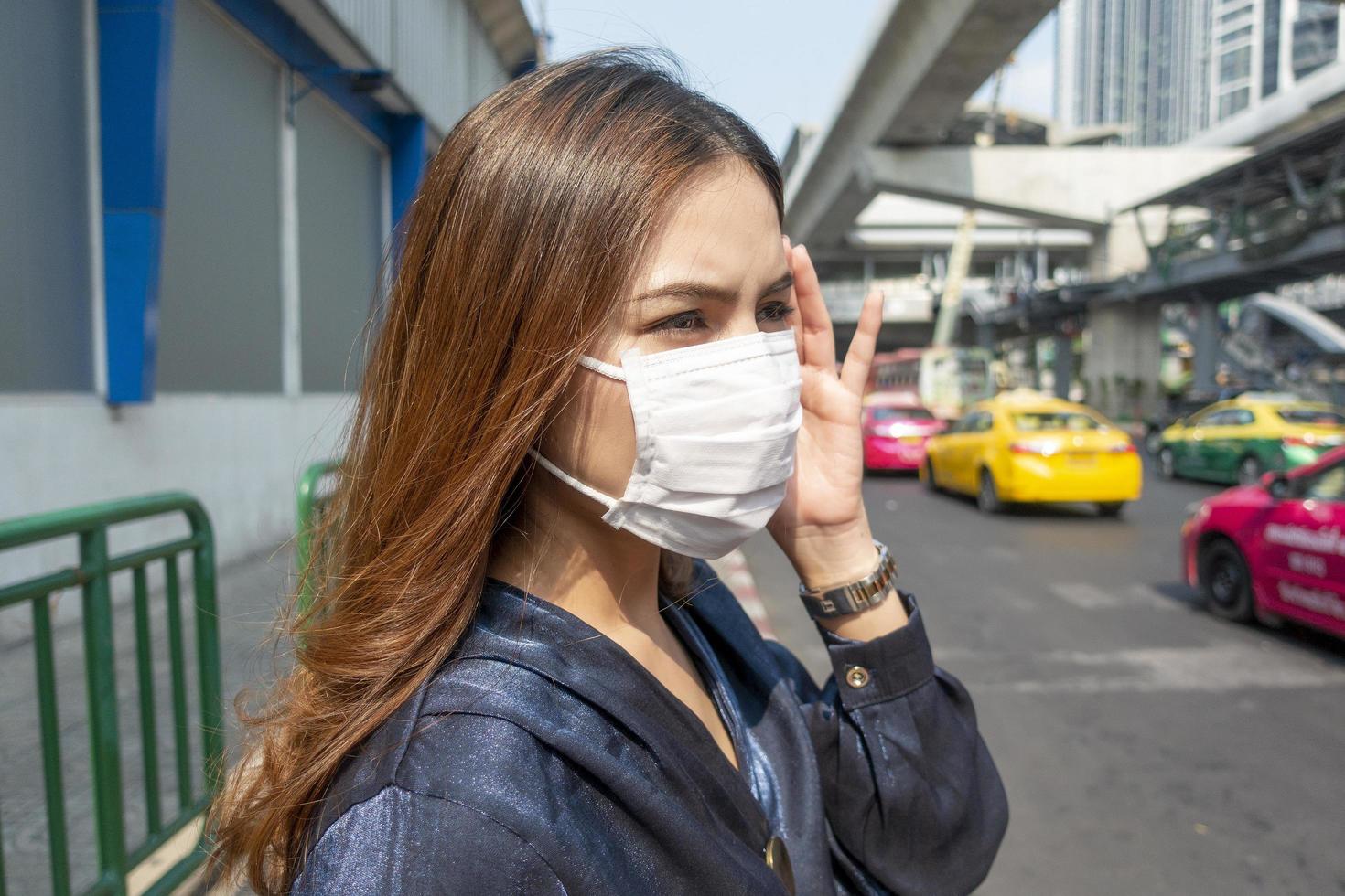 bella donna che indossa una maschera antipolvere protegge l'inquinamento atmosferico e pm 2.5 sulla città di strada foto