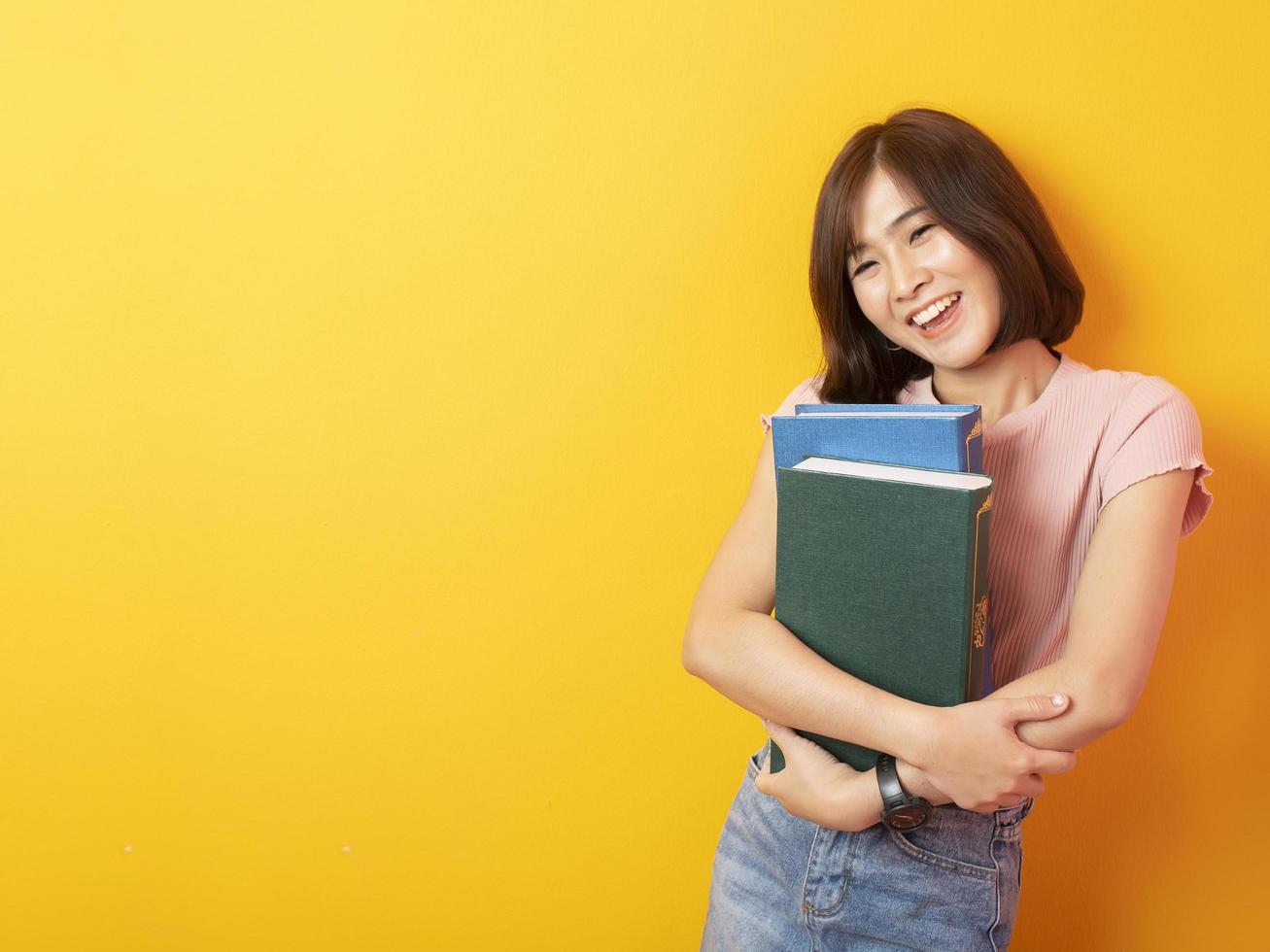 bella studentessa universitaria asiatica felice su sfondo giallo foto