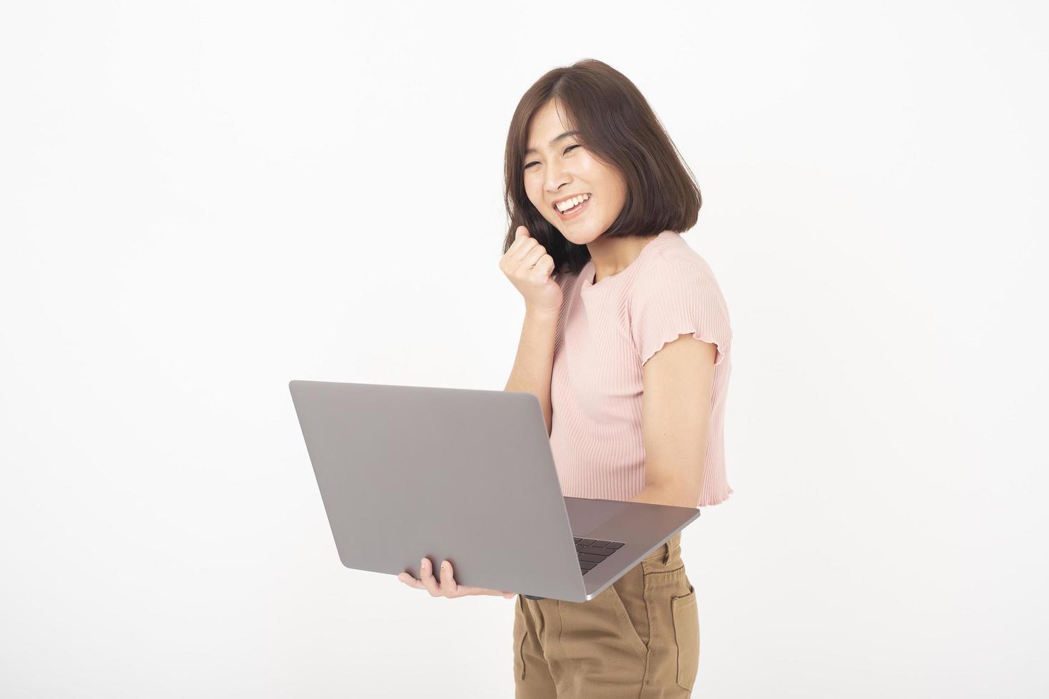 la donna teenager asiatica sveglia sta lavorando con il computer su priorità bassa bianca foto