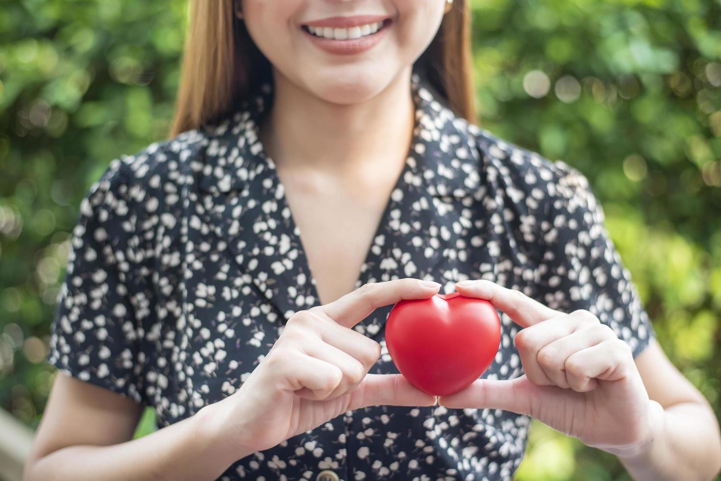 la mano della donna tiene il concetto di cuore rosso, amore e assistenza sanitaria foto