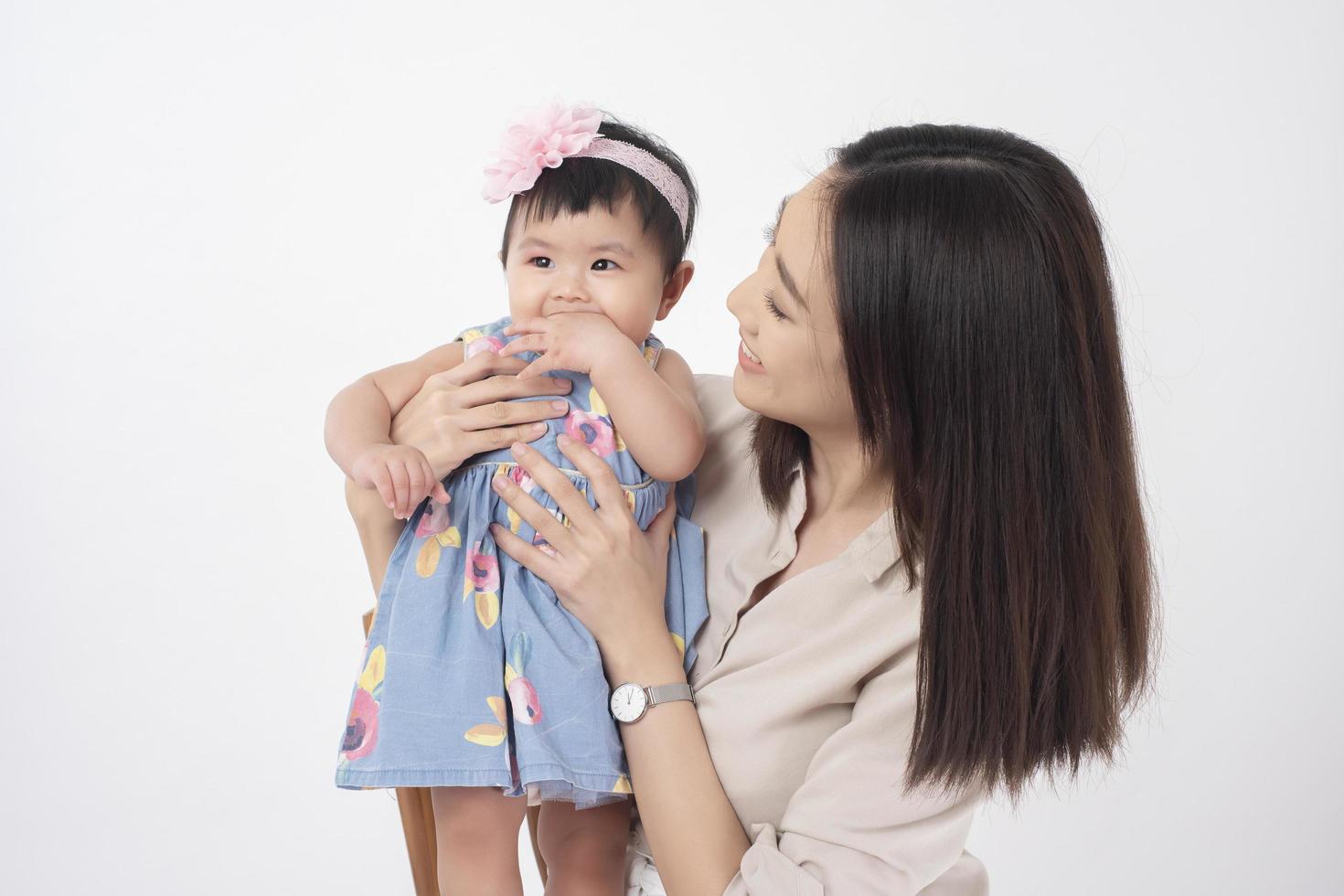 la madre asiatica e la neonata adorabile sono felici su fondo bianco foto