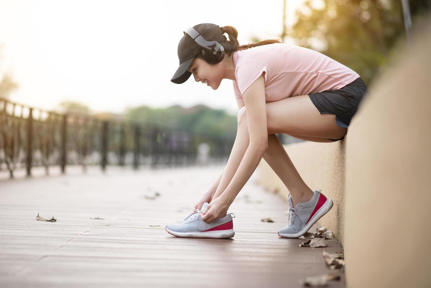 bella donna sta ascoltando musica e allaccia le scarpe nel parco foto