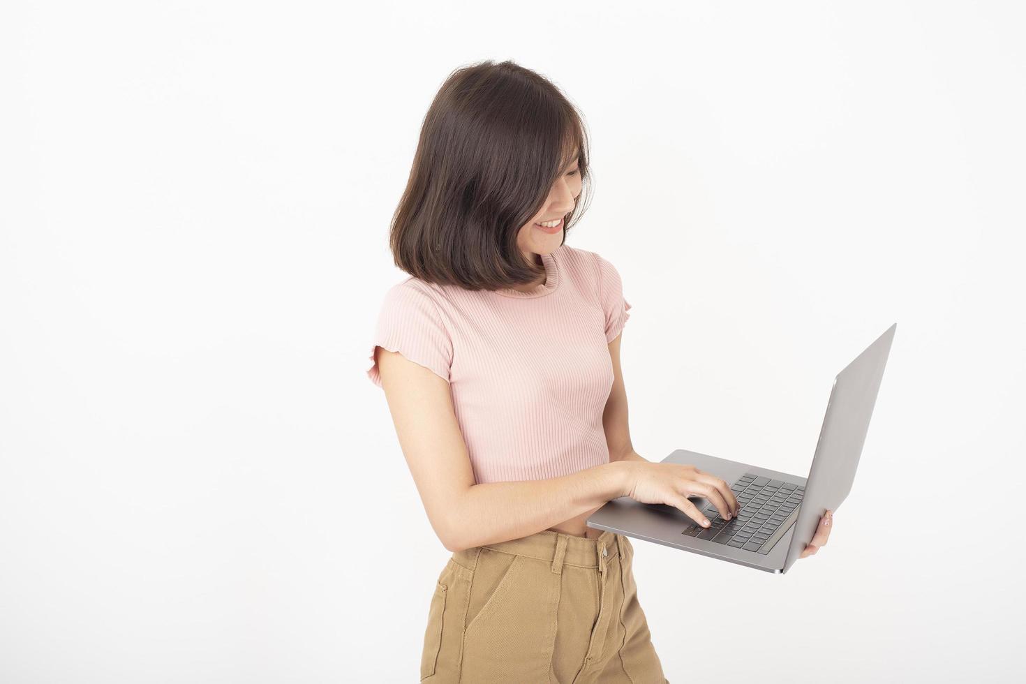 la donna teenager asiatica sveglia sta lavorando con il computer su priorità bassa bianca foto