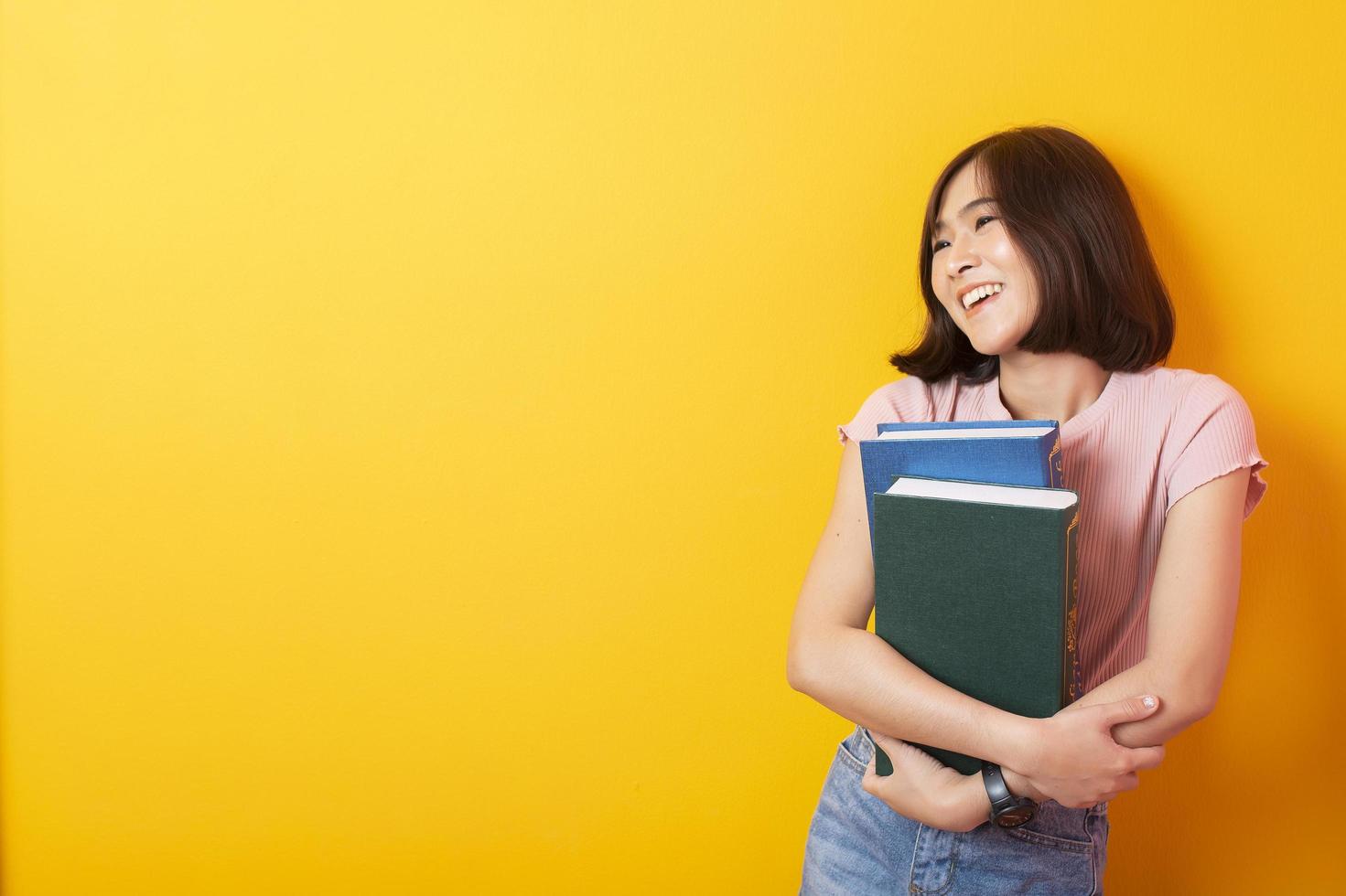 bella studentessa universitaria asiatica felice su sfondo giallo foto