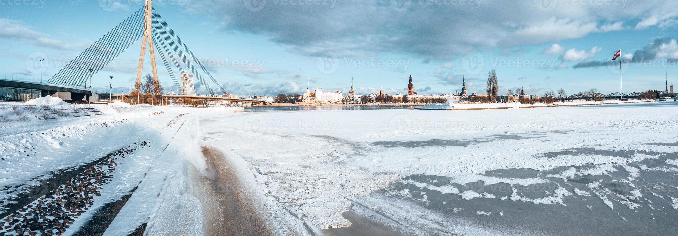 bellissima vista sul fiume ghiacciato con gabbiani seduti sul ghiaccio dal centro storico di riga in lettonia. foto