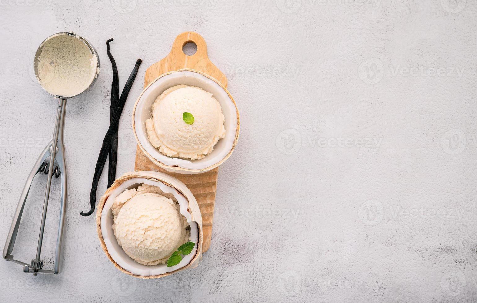 gusti di gelato al cocco a metà della configurazione di cocco su sfondo di pietra bianca. concetto di menu estivo e dolce. foto