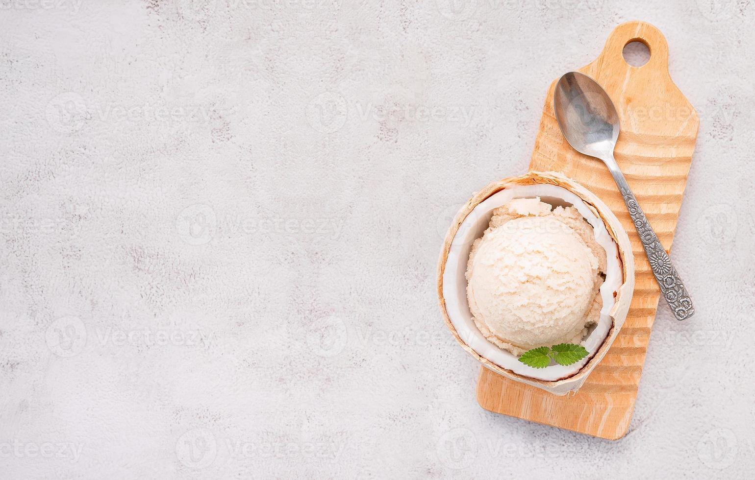 gusti di gelato al cocco a metà della configurazione di cocco su sfondo di pietra bianca. concetto di menu estivo e dolce. foto