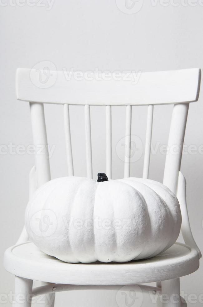 halloween e una zucca bianca su una sedia su sfondo bianco foto