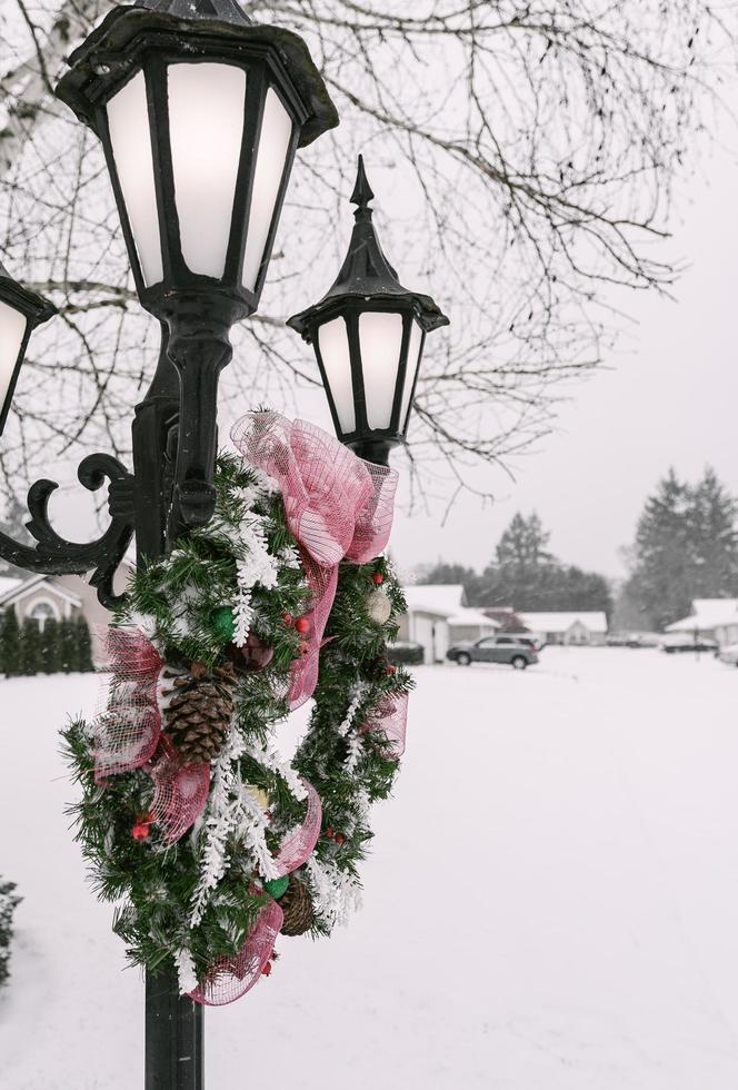 ghirlanda appoggiata su un lampione con la neve sullo sfondo foto