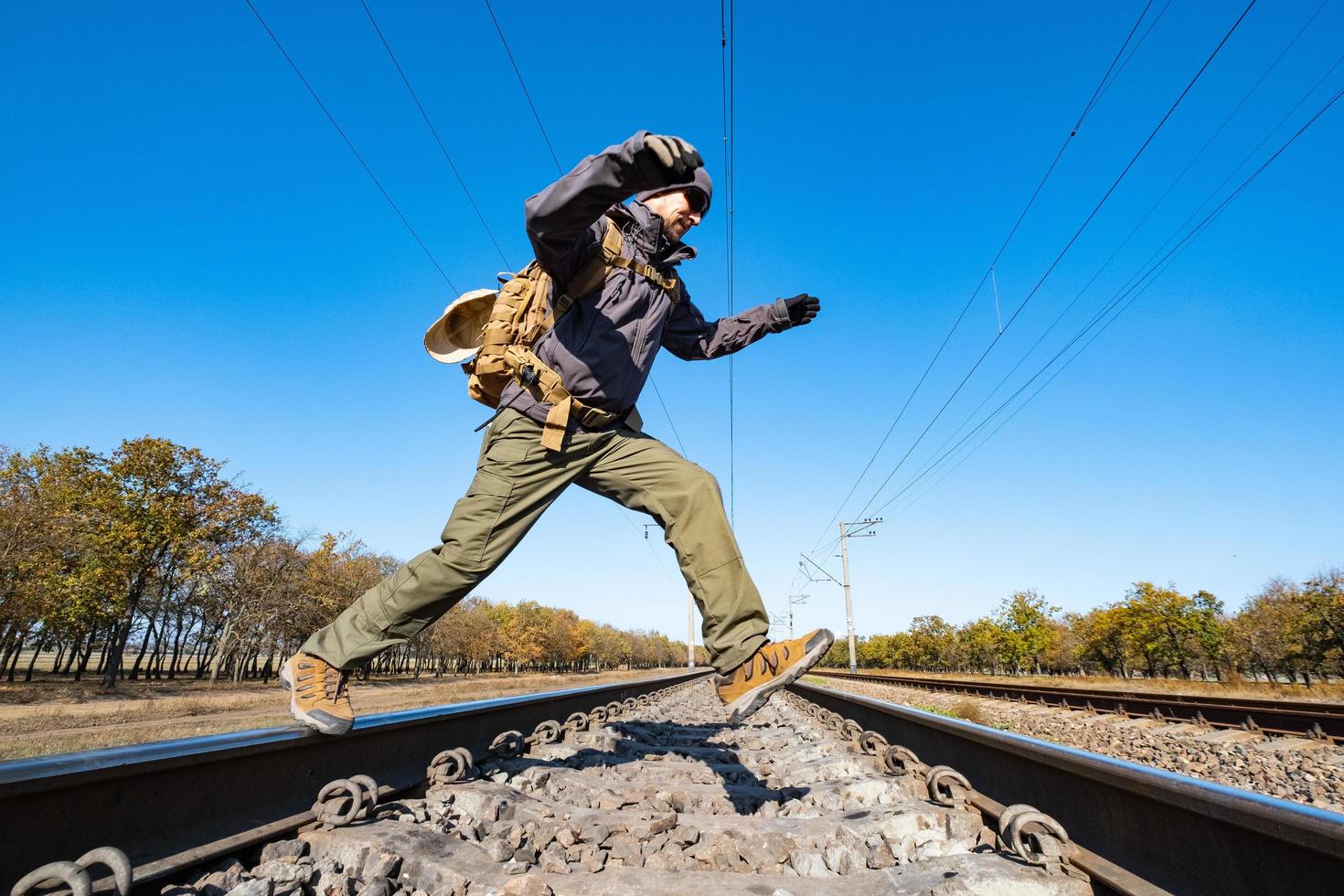 il viaggiatore maschio con equipaggiamento tattico e militare cammina da solo in una giornata di sole foto