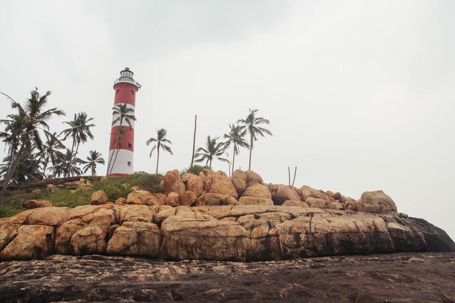 faro sulla spiaggia al cielo drammatico del mattino a kovalam, kerala, india. copia, spazio vuoto per il testo foto