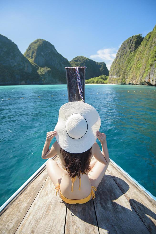 Vista della donna in costume da bagno godendo sulla tradizionale barca tailandese a coda lunga sulla bellissima montagna e sull'oceano, isole phi phi, tailandia foto