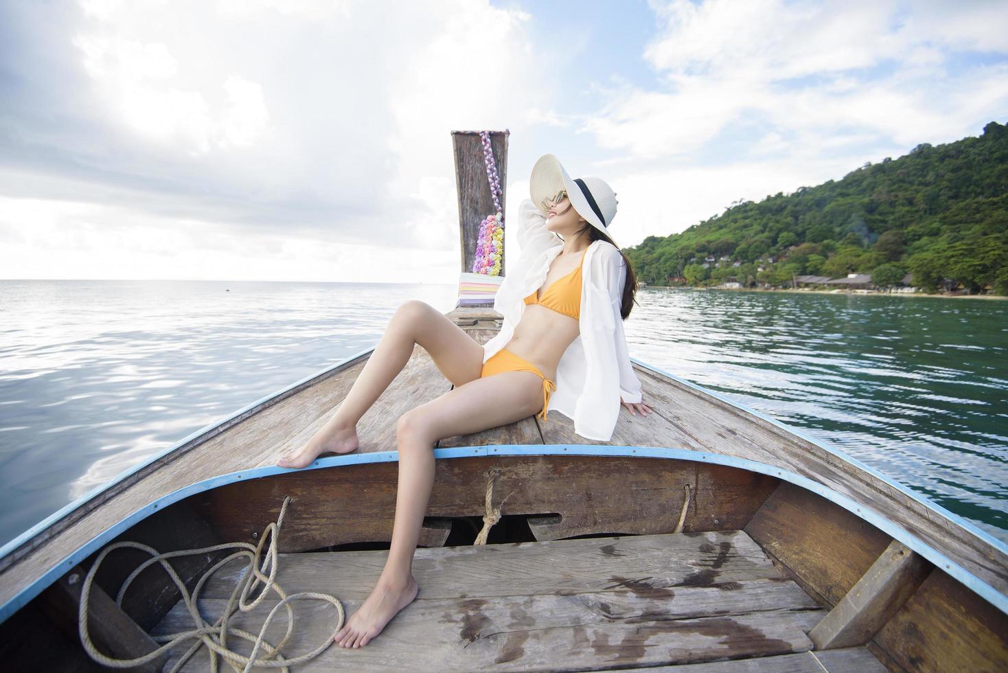 Vista della donna in costume da bagno godendo sulla tradizionale barca tailandese a coda lunga sulla bellissima montagna e sull'oceano, isole phi phi, tailandia foto