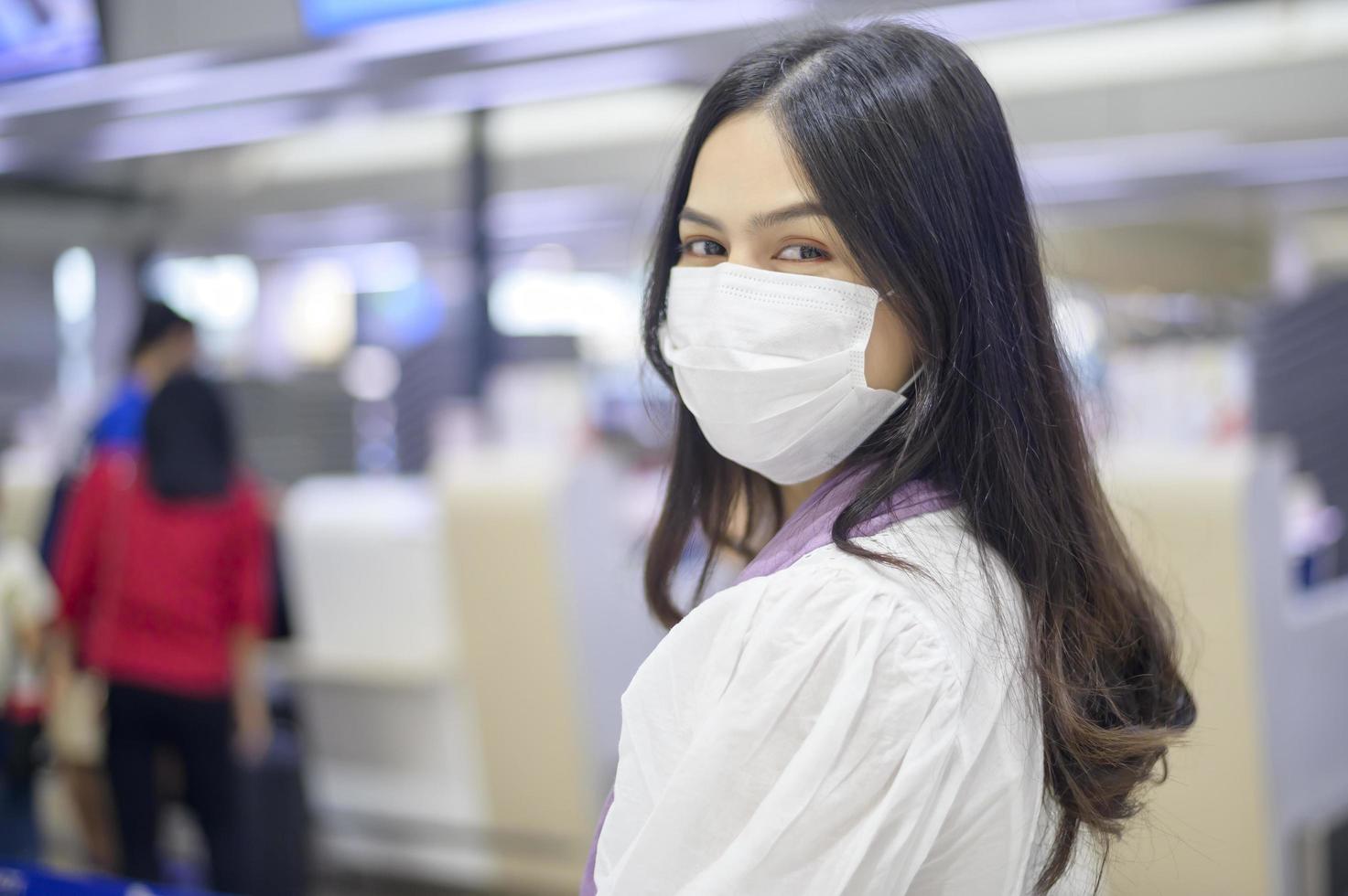 una donna viaggiatrice indossa una maschera protettiva nell'aeroporto internazionale, viaggia sotto la pandemia covid-19, viaggi di sicurezza, protocollo di allontanamento sociale, nuovo concetto di viaggio normale foto