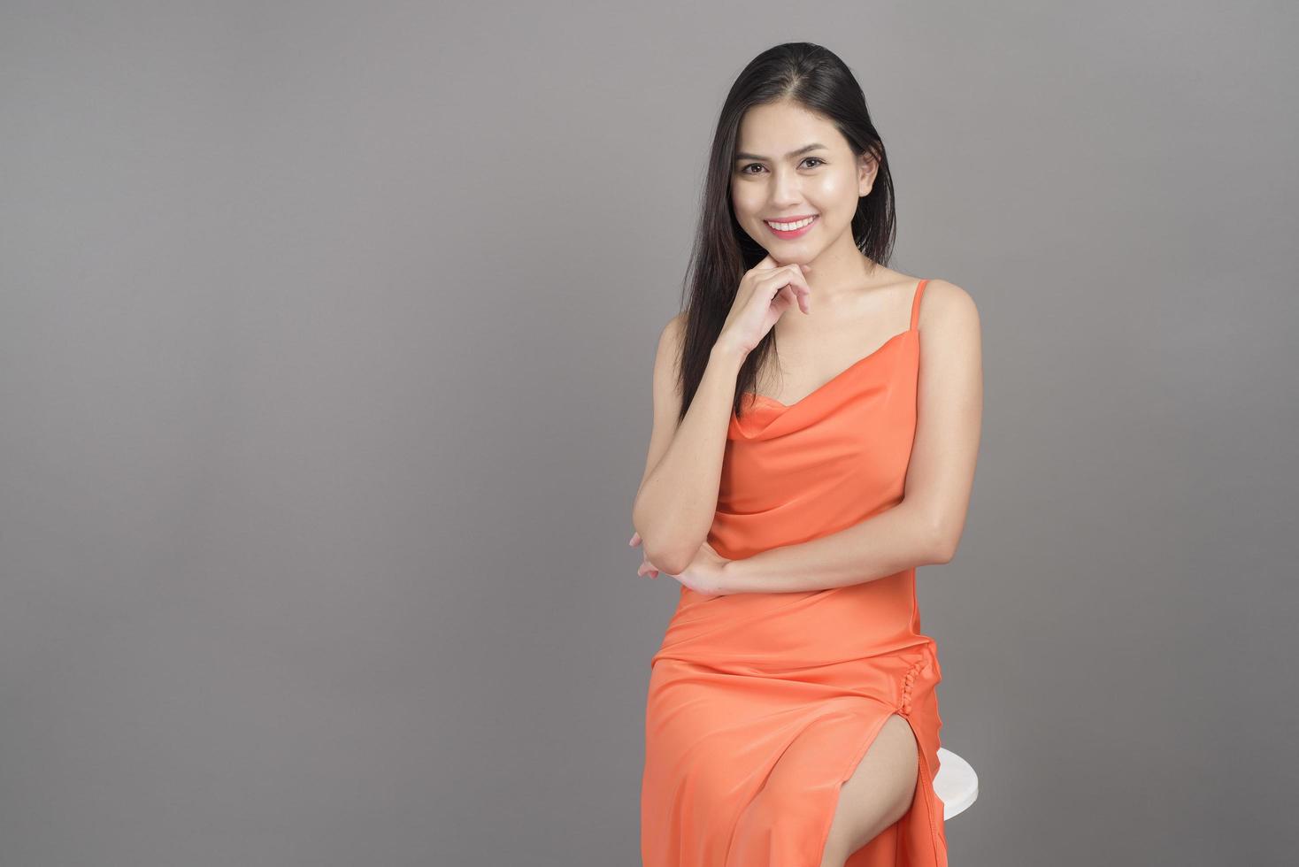 ritratto di moda di bella donna che indossa un abito arancione isolato su sfondo grigio studio foto
