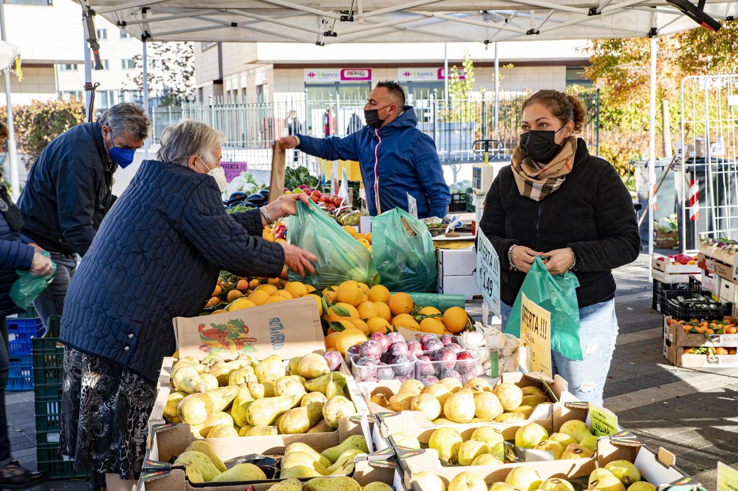 bancarella di frutta e verdura con venditore e clienti foto