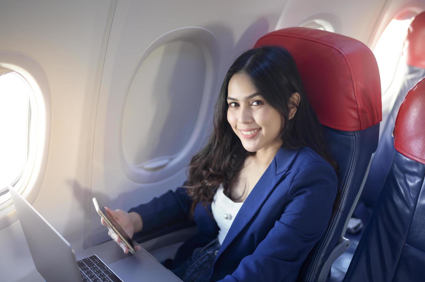 una giovane donna d'affari che indossa un abito blu sta usando il laptop a bordo foto