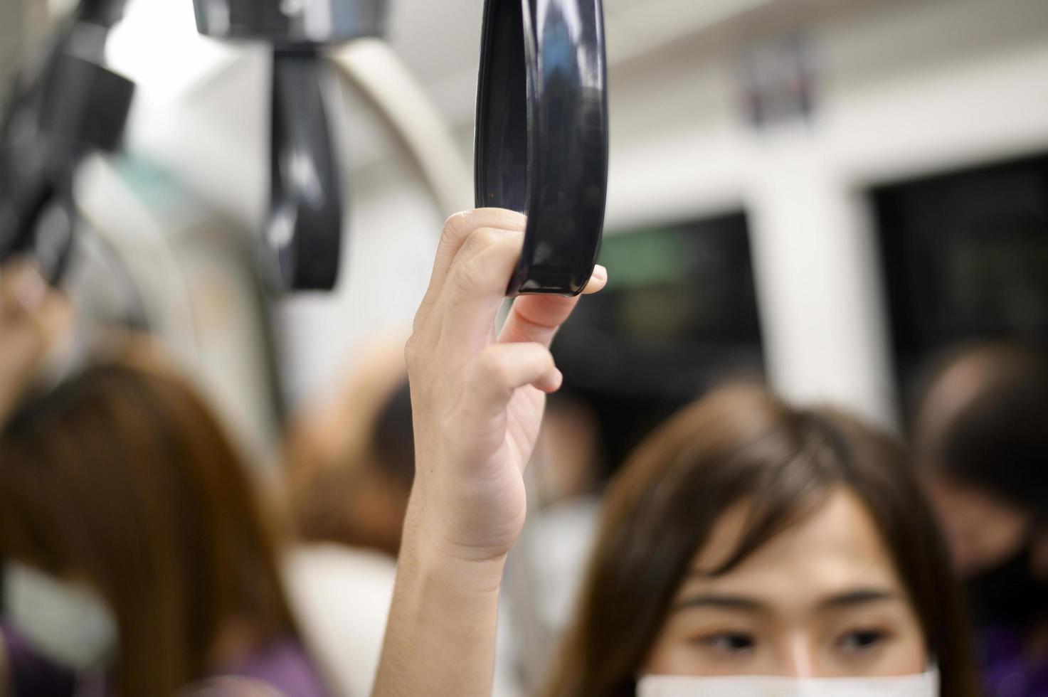 primo piano della mano della donna che tiene il corrimano nel treno del cielo della metropolitana dei trasporti pubblici foto